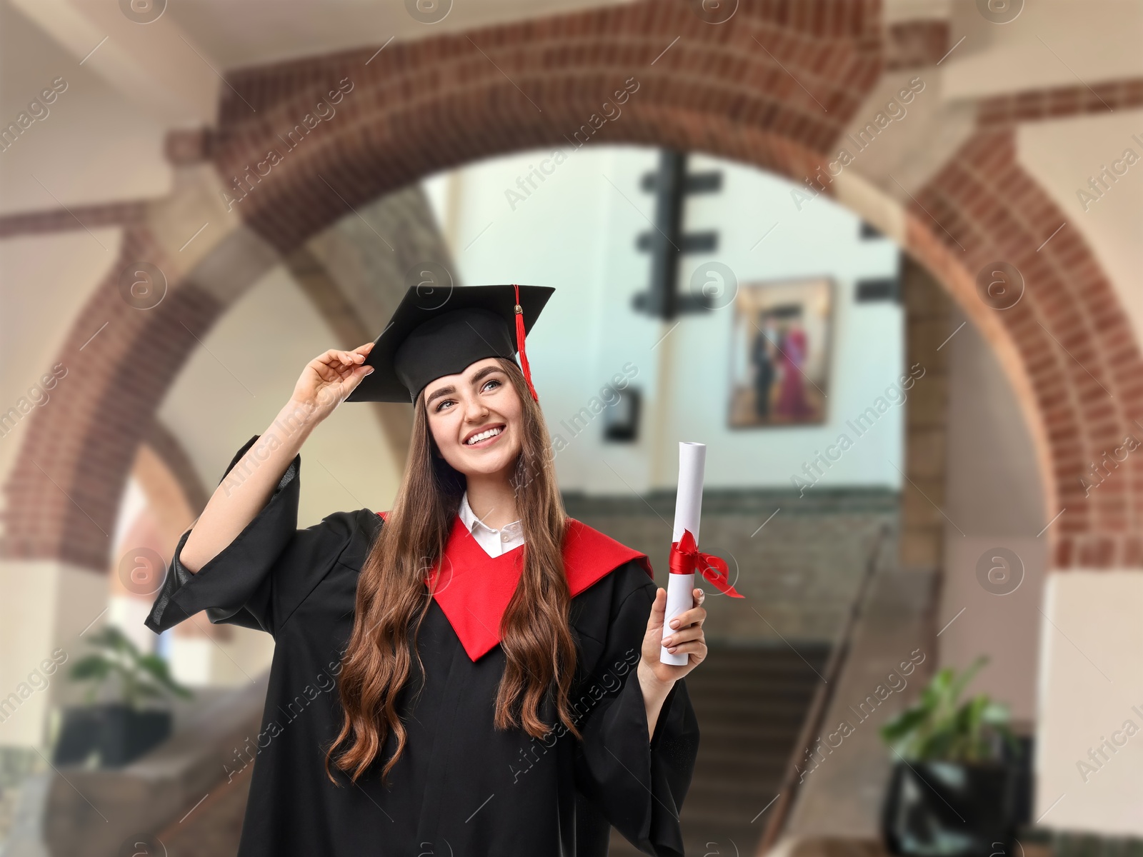 Image of Happy student in academic dress holding diploma after graduation in university