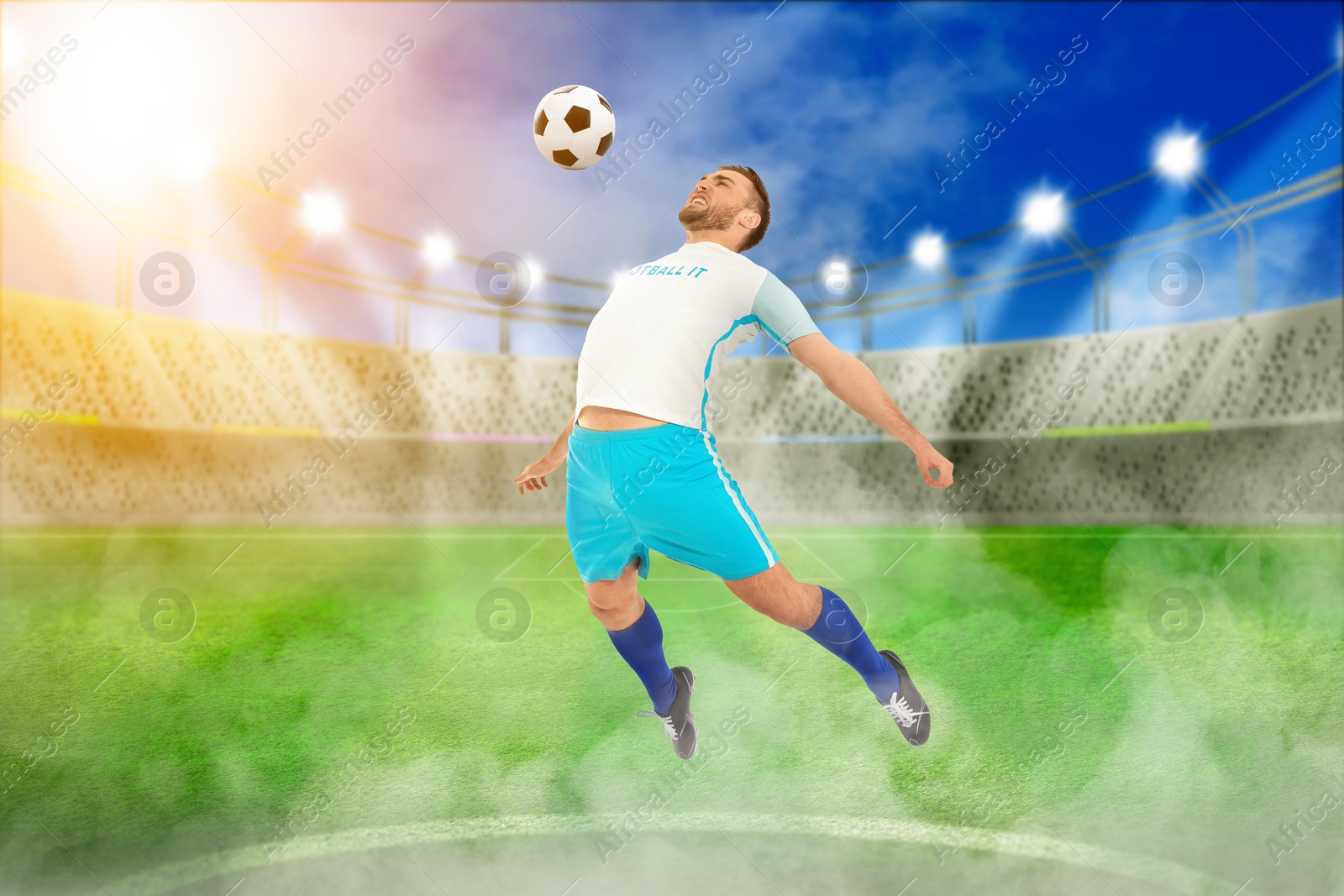 Image of Young man playing football under lights at stadium