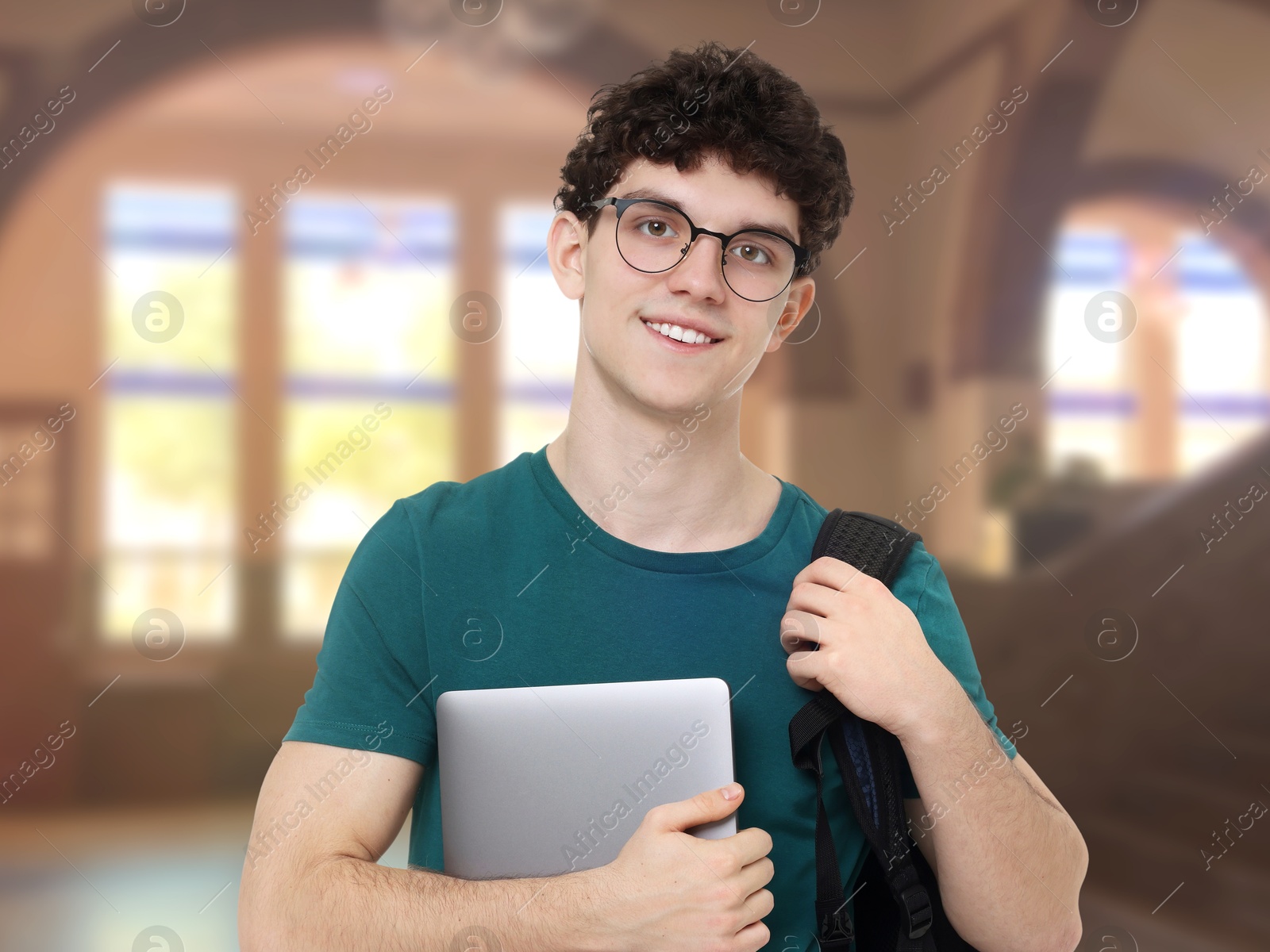 Image of Teenage student with eyeglasses, laptop and backpack in college