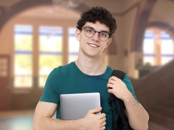 Image of Teenage student with eyeglasses, laptop and backpack in college