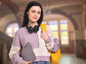 Image of Teenage student with headphones, laptop and backpack in college