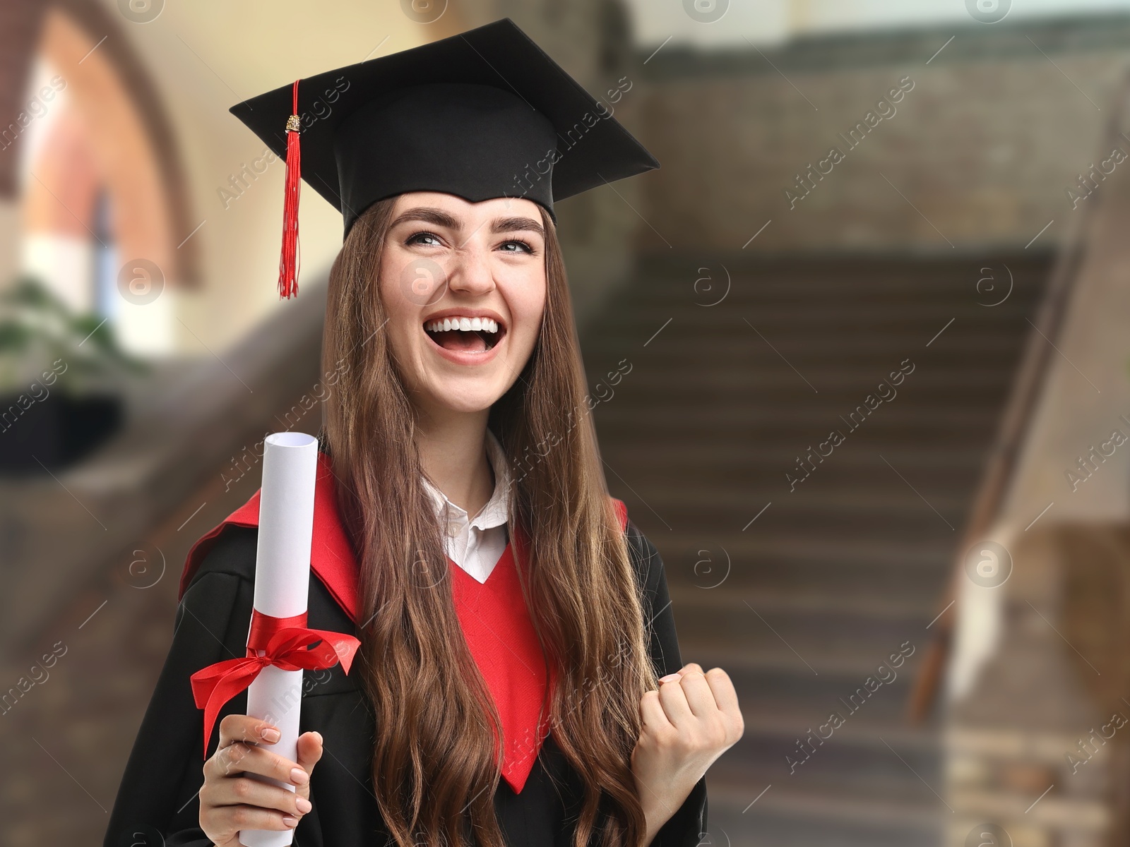 Image of Happy student in academic dress holding diploma after graduation in university