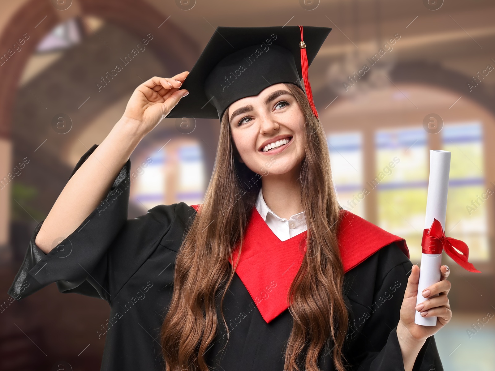 Image of Happy student in academic dress holding diploma after graduation in university