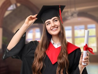 Image of Happy student in academic dress holding diploma after graduation in university