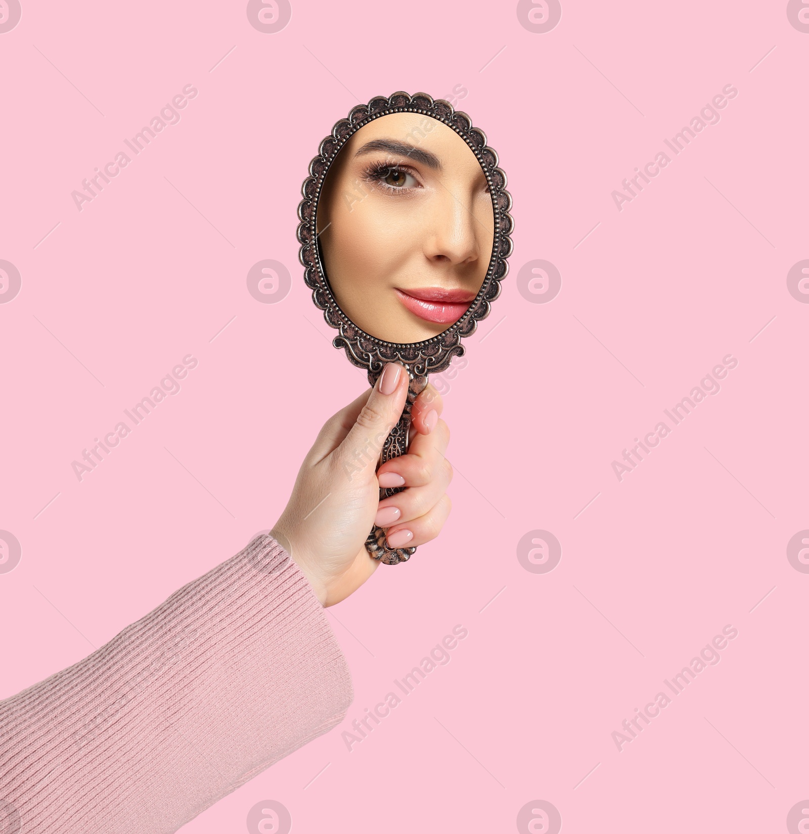 Image of Beautiful woman looking in handheld mirror on pink background, closeup