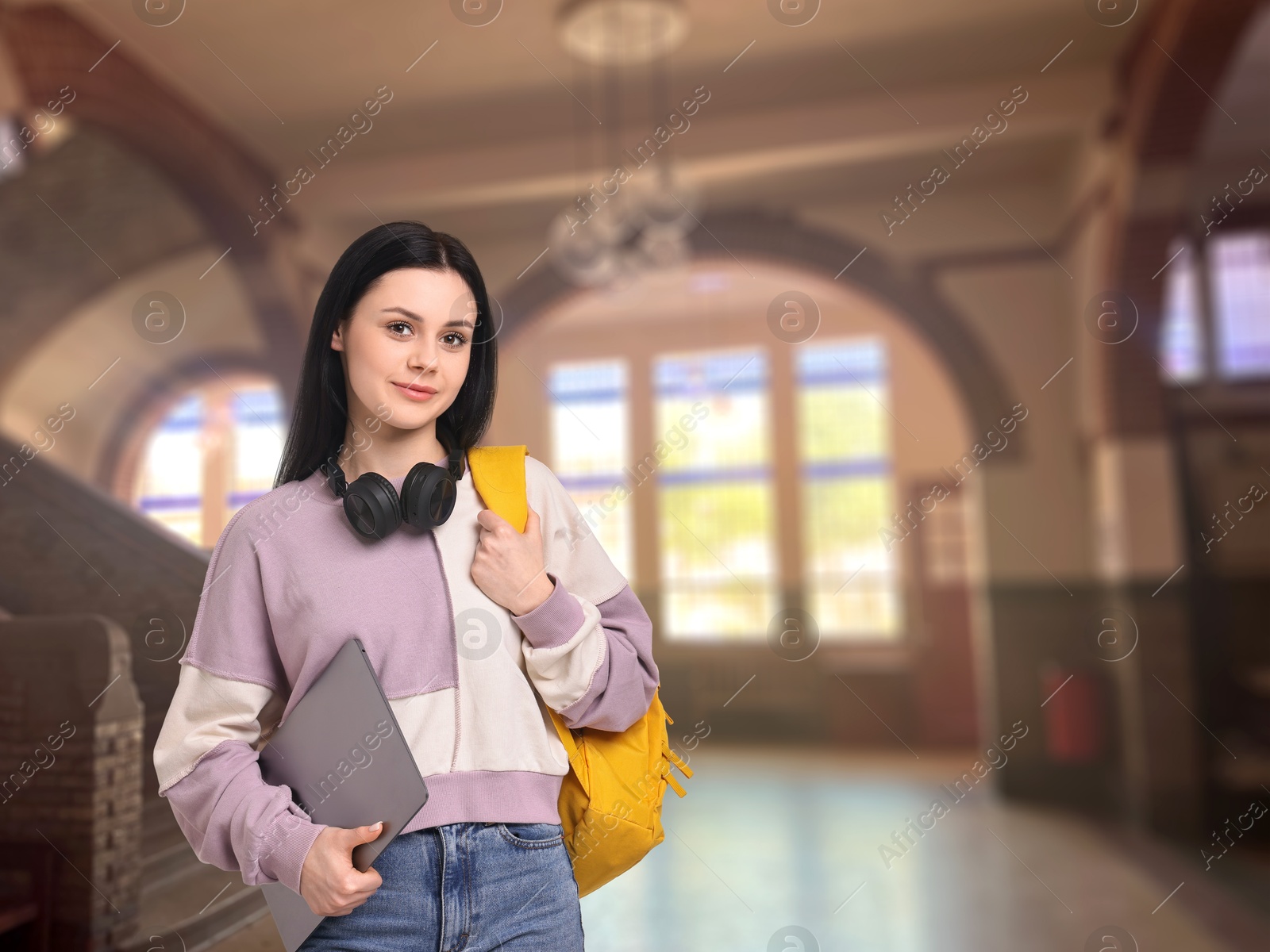 Image of Teenage student with headphones, laptop and backpack in college