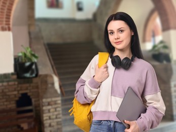 Image of Teenage student with headphones, laptop and backpack in college