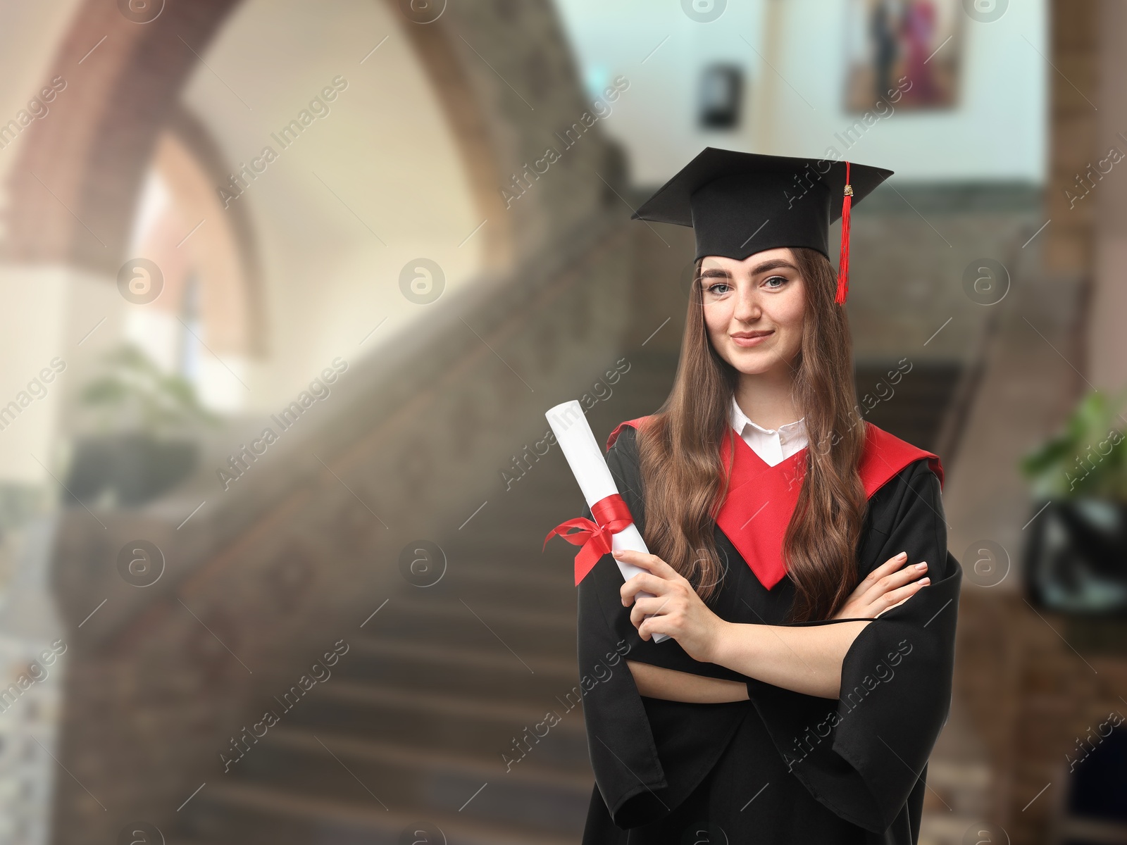 Image of Happy student in academic dress holding diploma after graduation in university