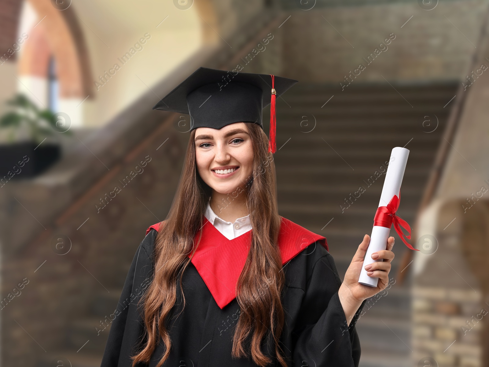 Image of Happy student in academic dress holding diploma after graduation in university