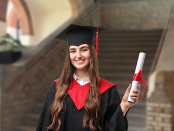 Image of Happy student in academic dress holding diploma after graduation in university