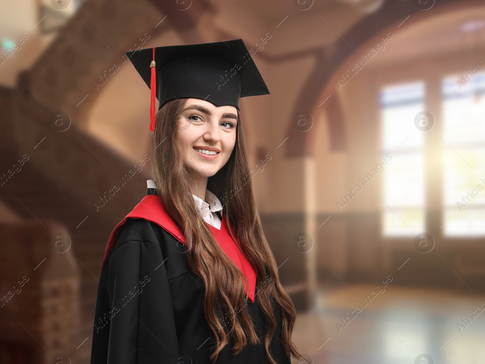 Image of Happy student wearing academic dress during graduation in university