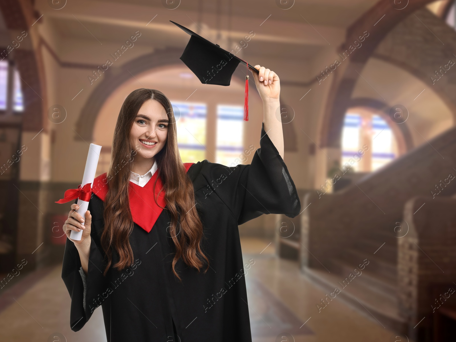 Image of Happy student in academic dress holding diploma after graduation in university