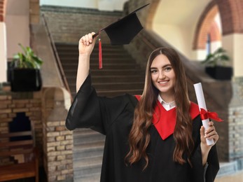 Image of Happy student in academic dress holding diploma after graduation in university