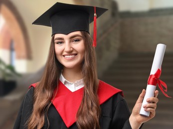 Image of Happy student in academic dress holding diploma after graduation in university