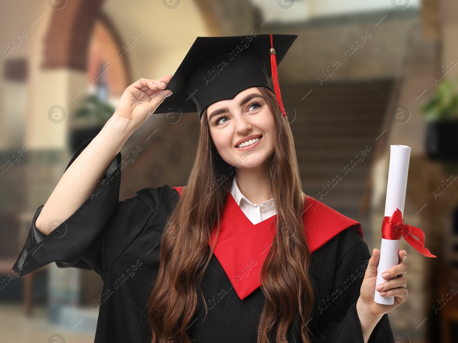 Image of Happy student in academic dress holding diploma after graduation in university