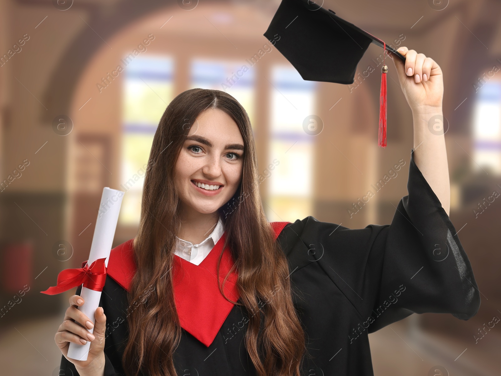 Image of Happy student in academic dress holding diploma after graduation in university