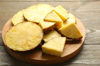 Photo of Slices of ripe pineapple on wooden table, closeup