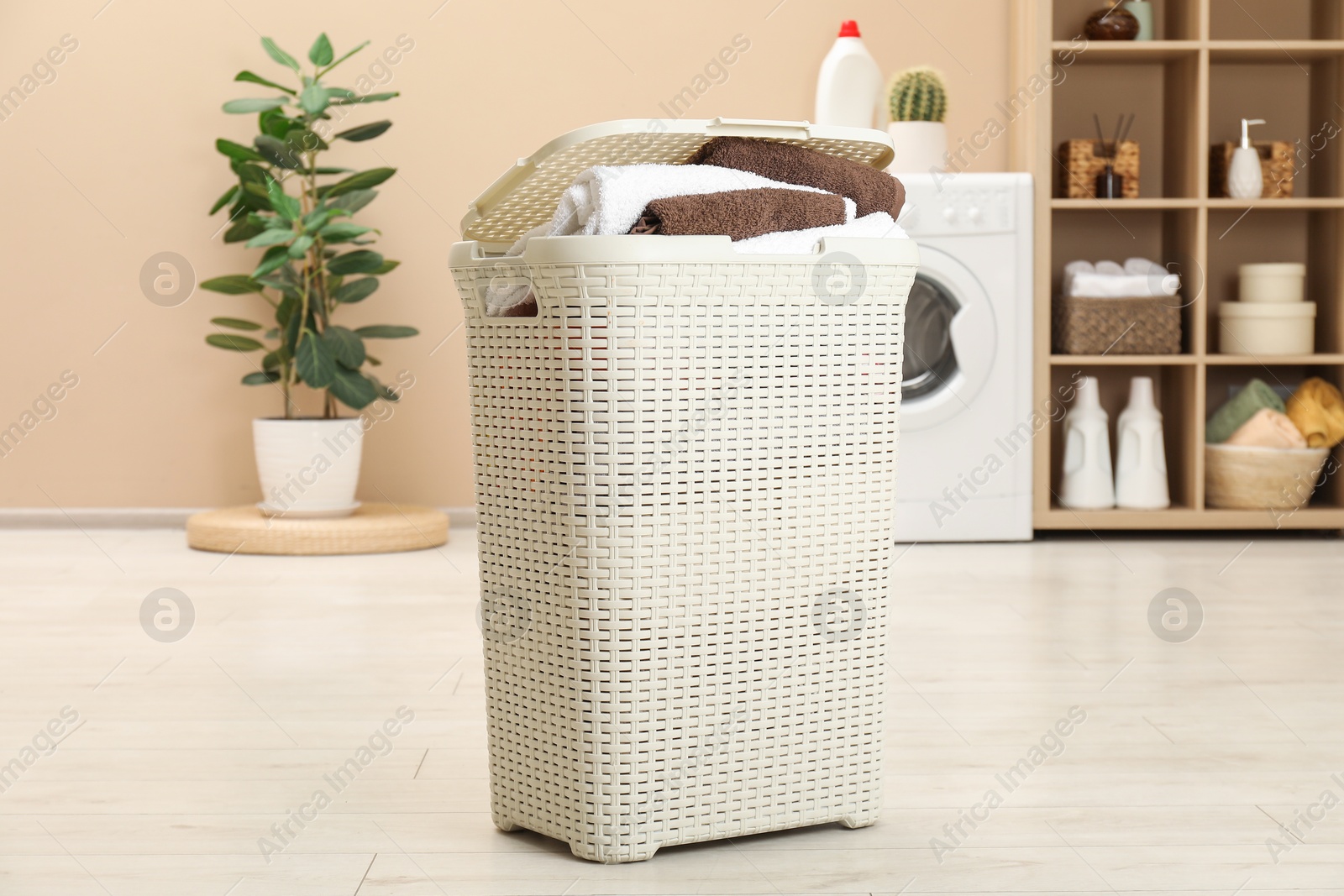 Photo of Wicker basket full of laundry in bathroom