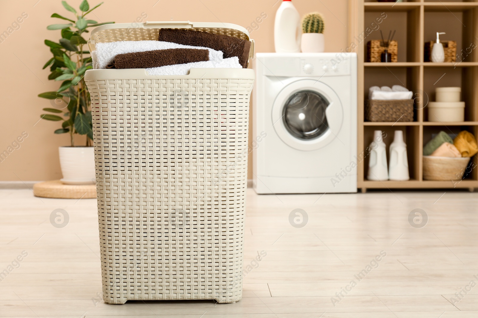 Photo of Wicker basket full of laundry in bathroom