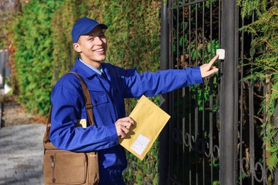 Photo of Postman with parcel ringing entrance bell outdoors