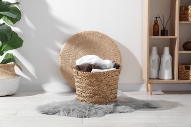 Photo of Wicker basket full of laundry in bathroom