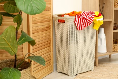 Photo of Wicker basket full of laundry in bathroom