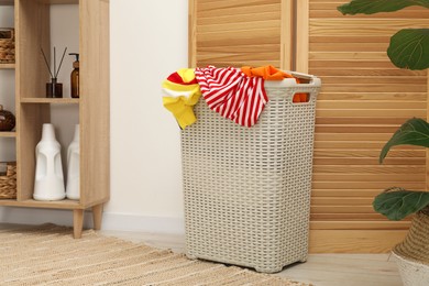 Photo of Wicker basket full of laundry in bathroom