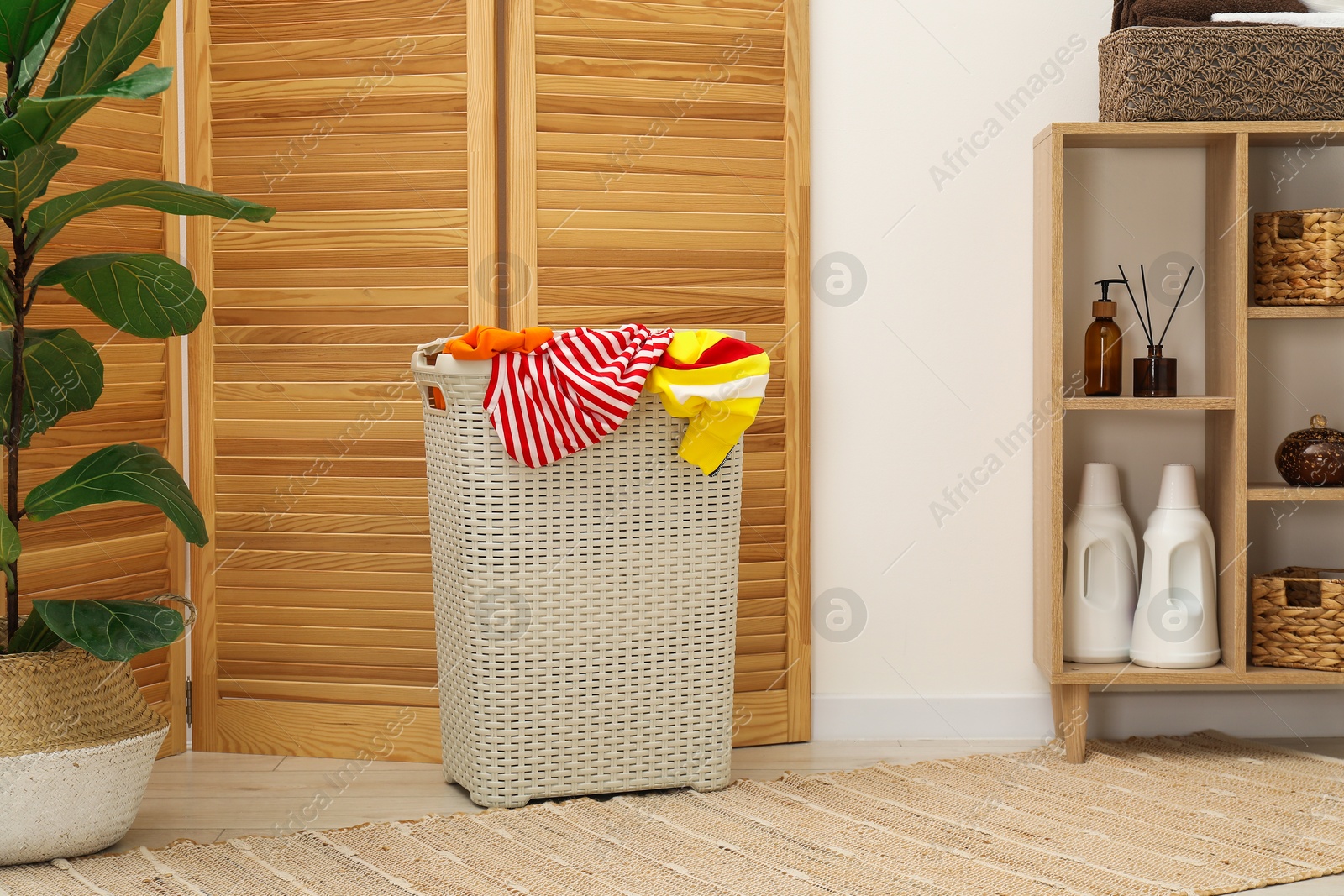 Photo of Wicker basket full of laundry in bathroom