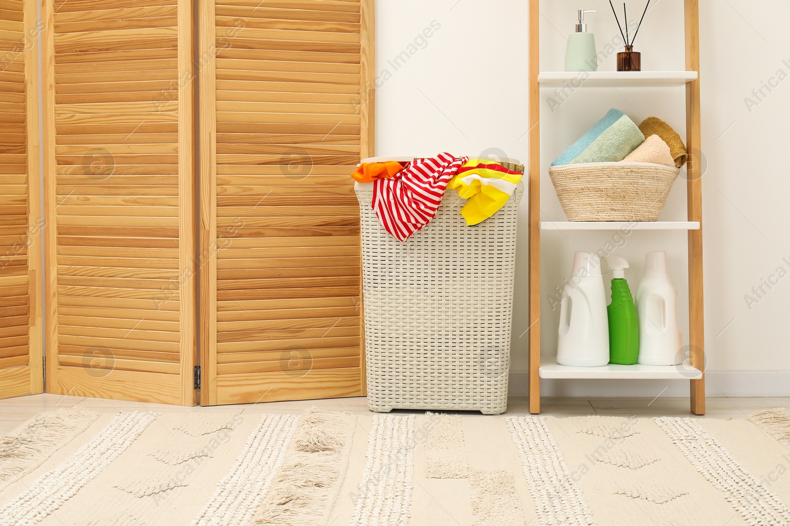 Photo of Wicker basket full of laundry, detergents and toiletries in bathroom