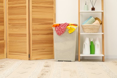 Photo of Wicker basket full of laundry, detergents and toiletries in bathroom