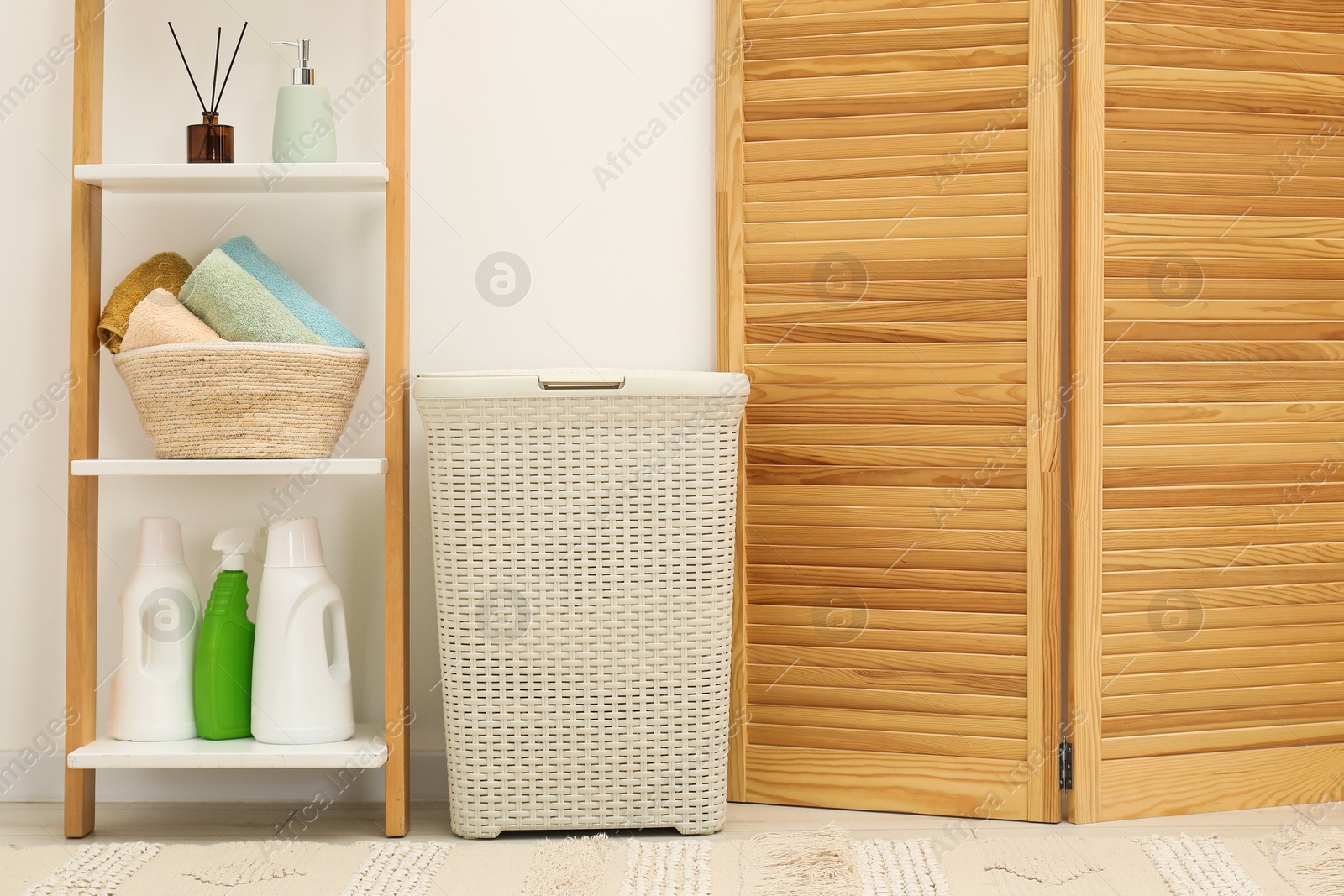 Photo of Wicker laundry basket, towels and detergents in bathroom