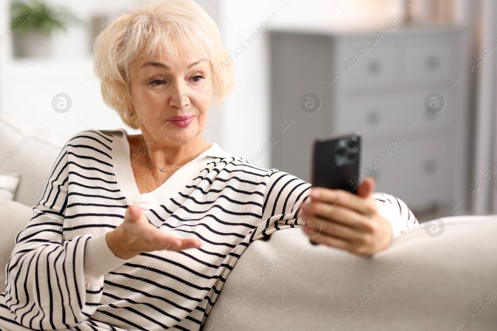 Photo of Beautiful grandmother having video chat via smartphone at home