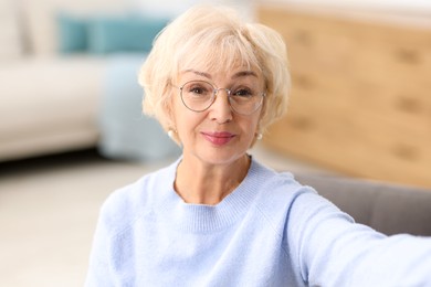 Photo of Grandmother with beautiful makeup taking selfie at home