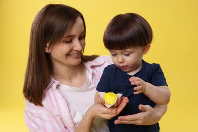 Photo of Mother and baby eating tasty mochi on yellow background