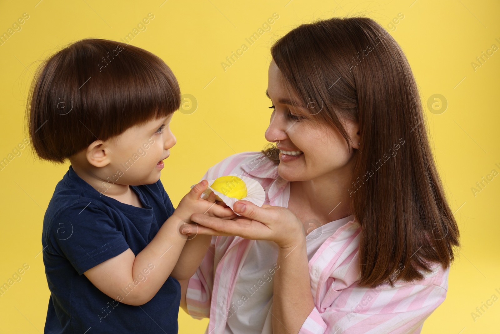 Photo of Mother and baby eating tasty mochi on yellow background