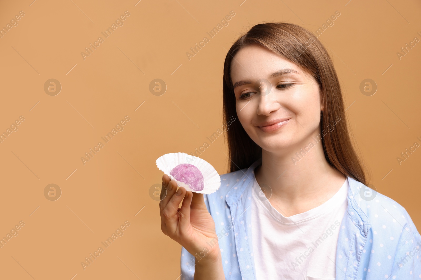 Photo of Woman with tasty mochi on light brown background. Space for text