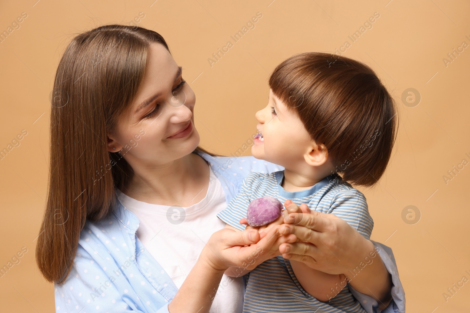 Photo of Mother and baby eating tasty mochi on brown background