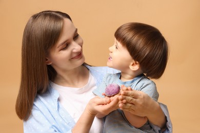 Photo of Mother and baby eating tasty mochi on brown background