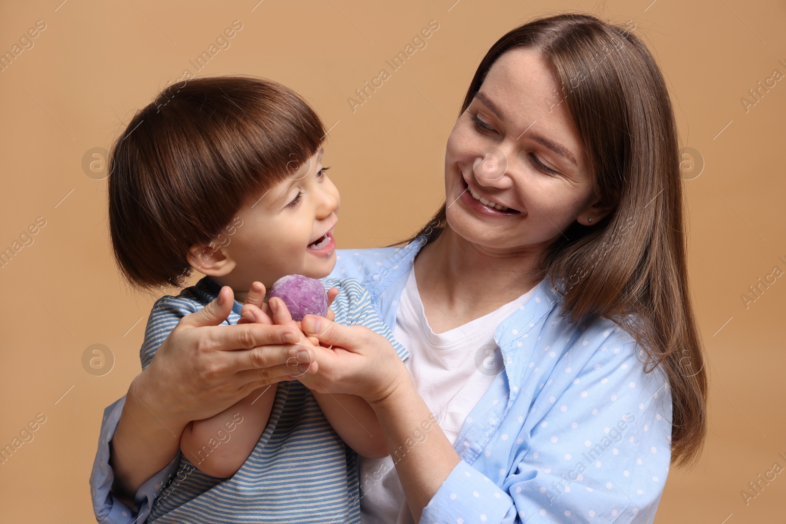 Photo of Mother and baby eating tasty mochi on brown background