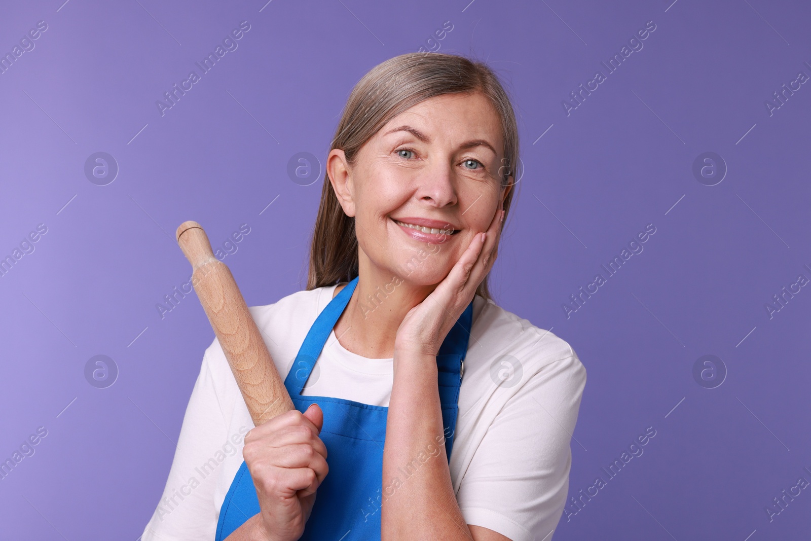 Photo of Happy woman with rolling pin on violet background