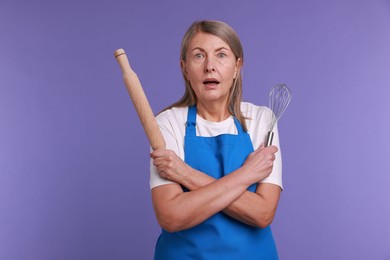 Photo of Surprised woman with rolling pin and whisk on violet background