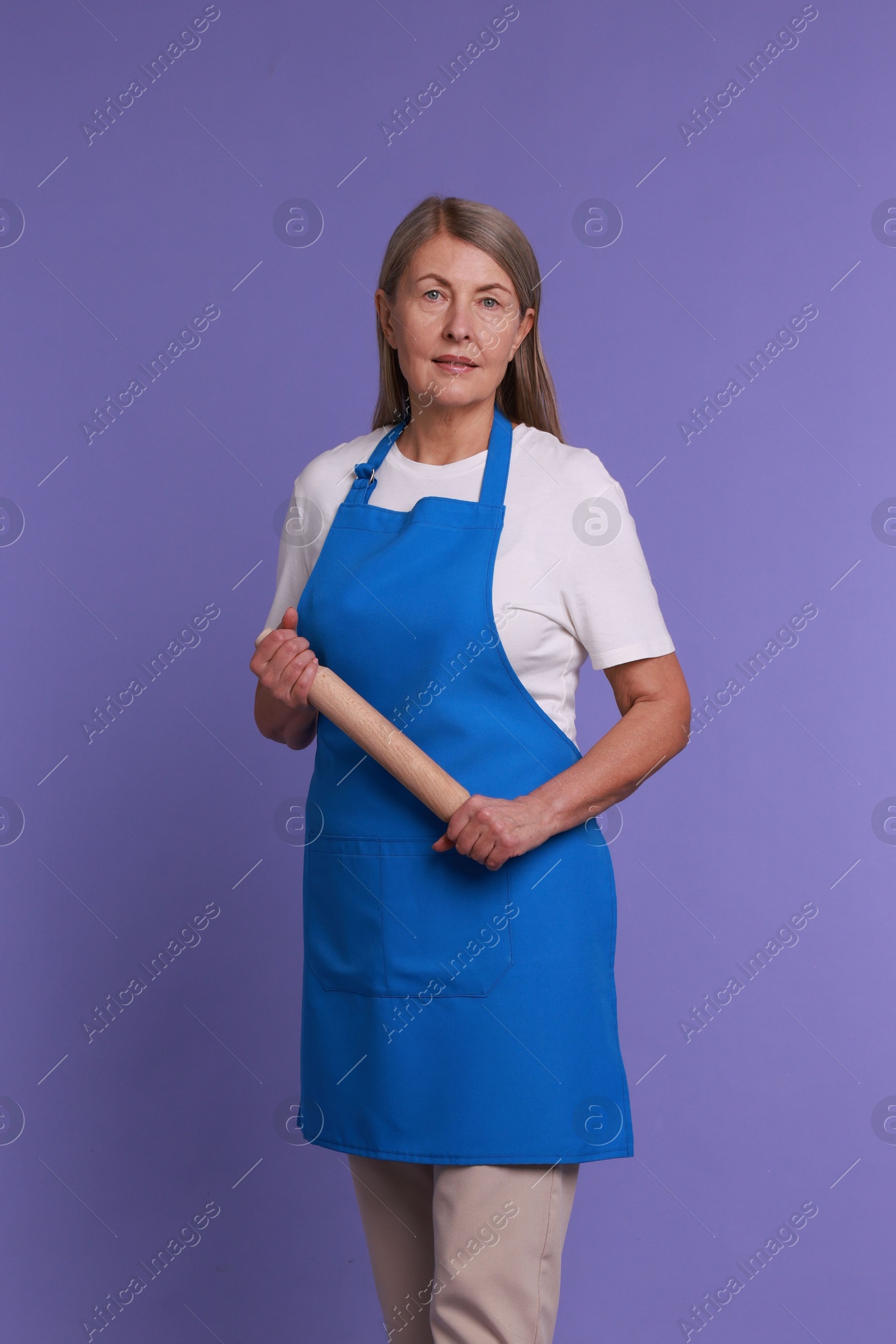 Photo of Woman with rolling pin on violet background