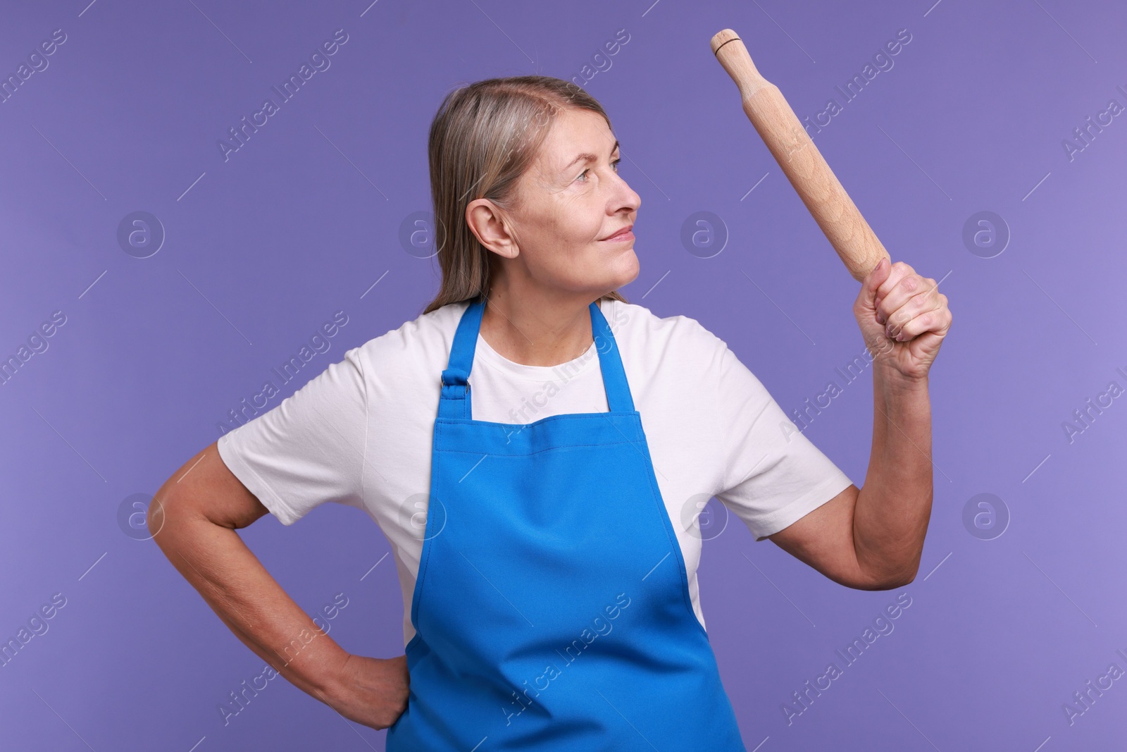 Photo of Woman with rolling pin on violet background