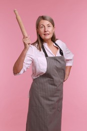 Photo of Emotional woman with rolling pin on pink background