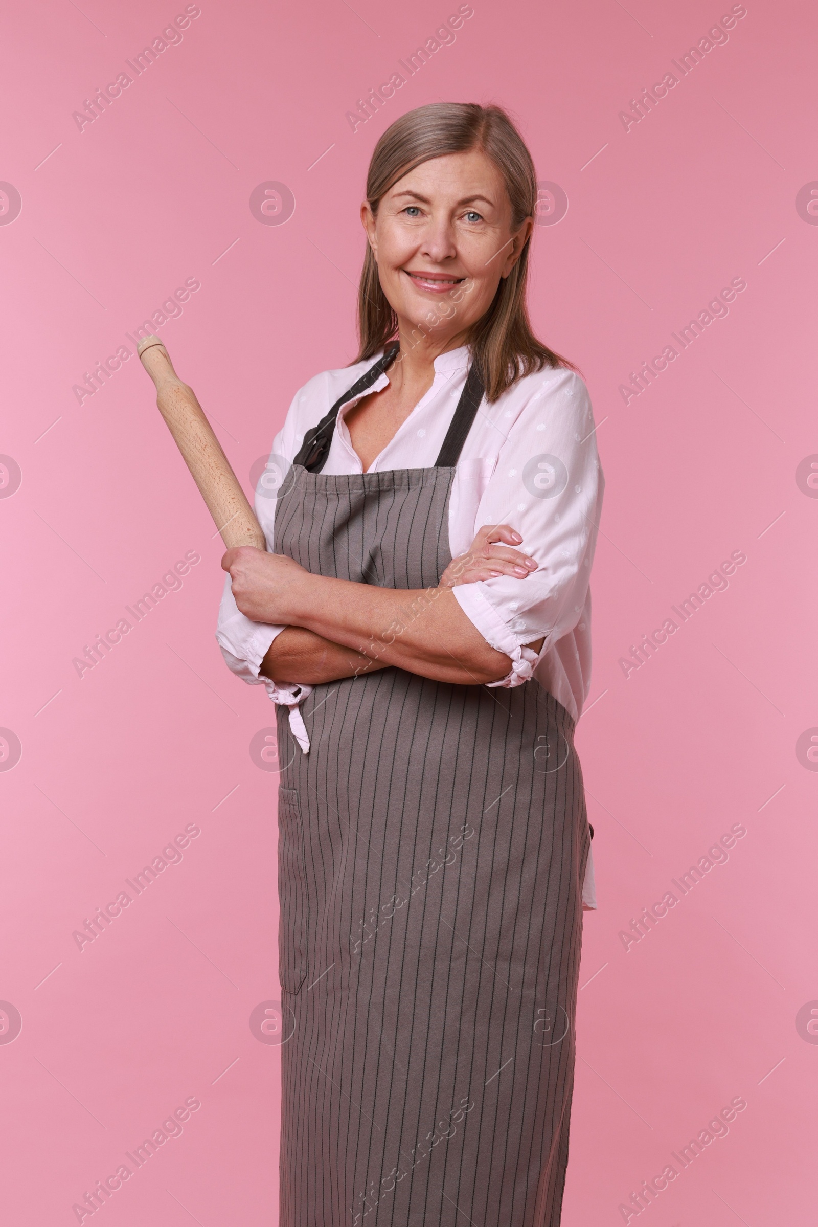 Photo of Happy woman with rolling pin on pink background