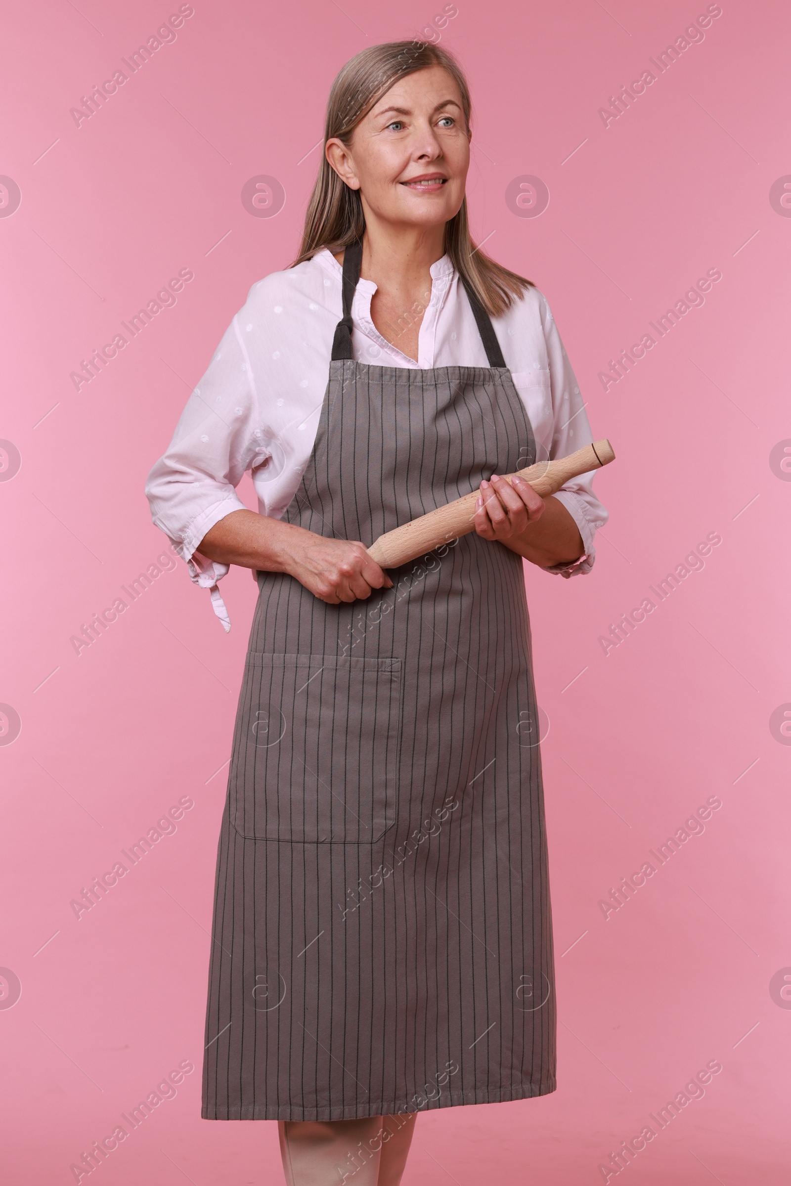 Photo of Happy woman with rolling pin on pink background