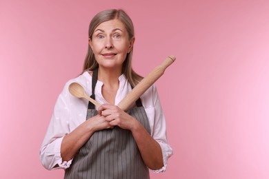 Photo of Happy woman with rolling pin and spoon on pink background. Space for text