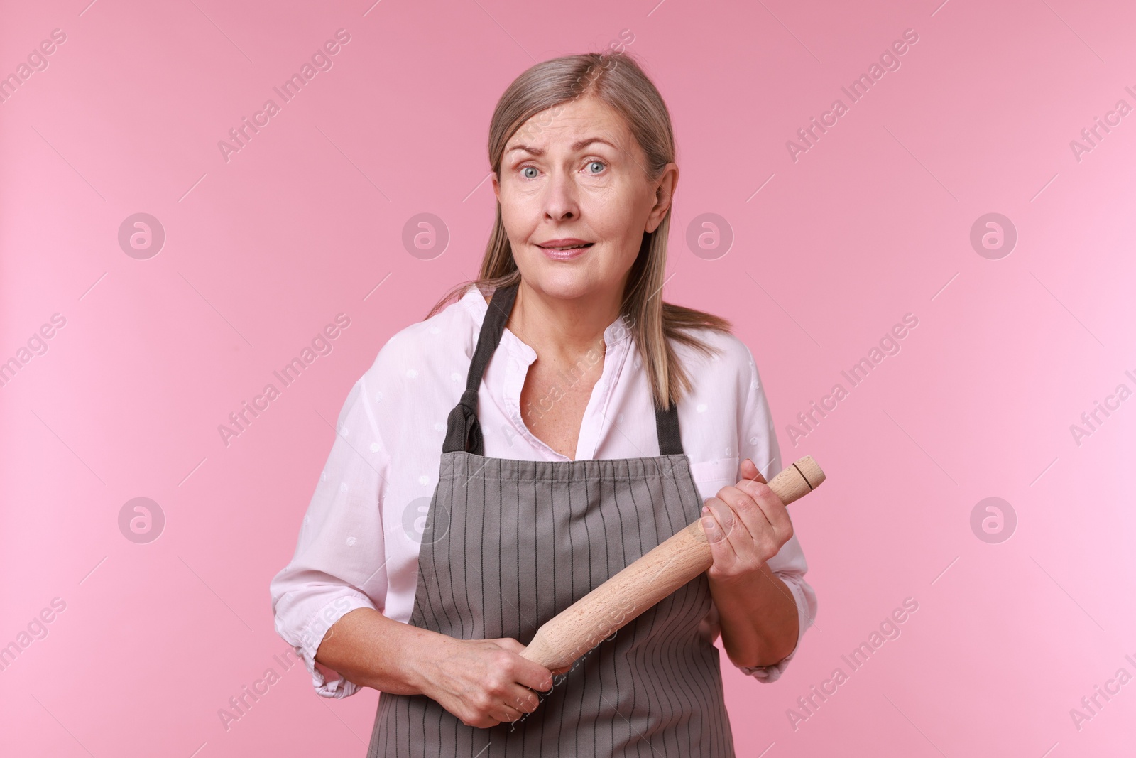 Photo of Emotional woman with rolling pin on pink background