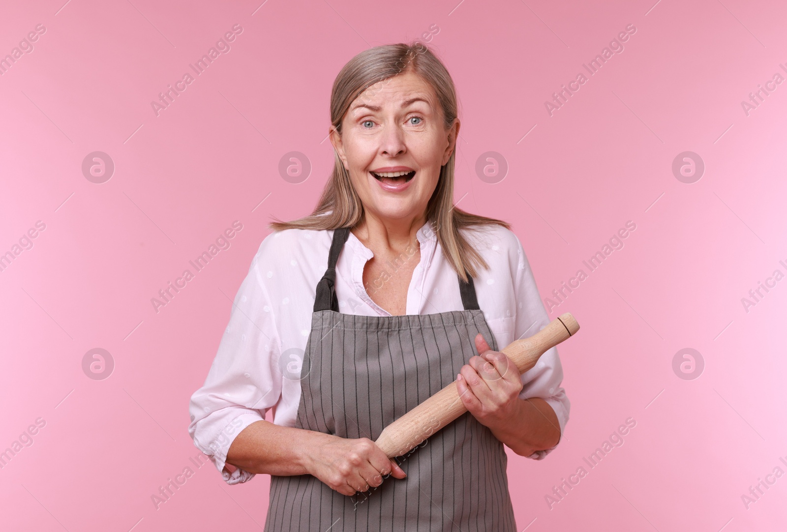 Photo of Emotional woman with rolling pin on pink background