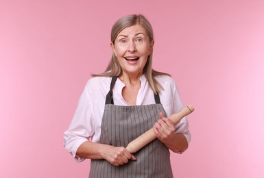 Photo of Emotional woman with rolling pin on pink background